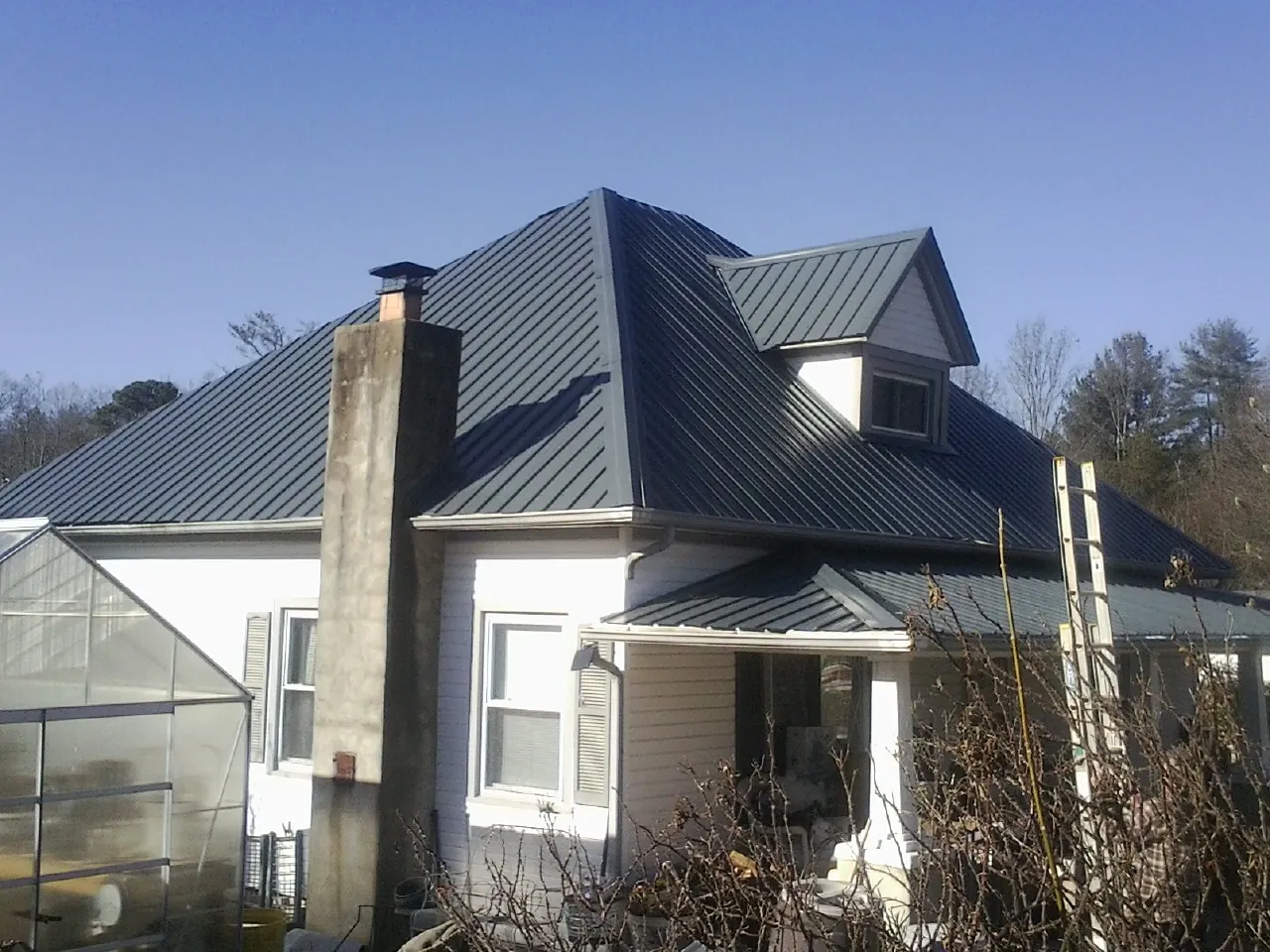 Dark blue standing seam metal roof on a white farmhouse with dormer — Slate & Tile Roof Repair by Roofing Brothers in Cusseta