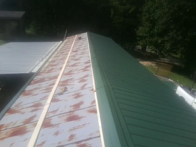 Old rusted panels beside newly installed green metal roofing — Wind Damage Roof Repair by Roofing Brothers in Cusseta