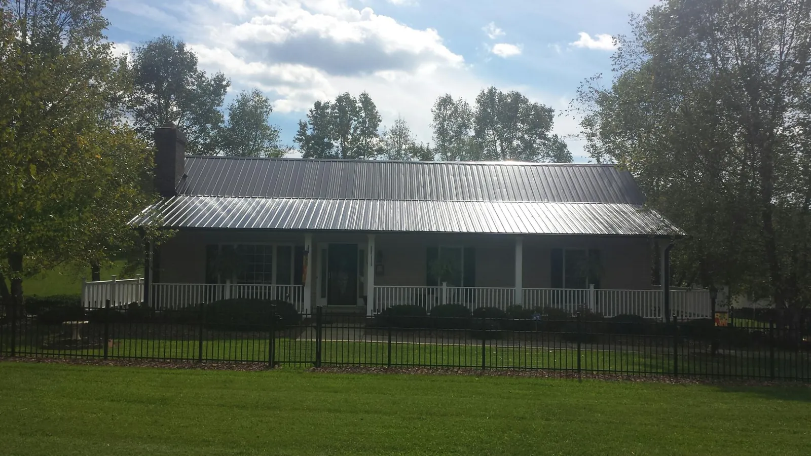 Gray metal roof on a brick ranch with a full width front porch — Gutter Guard Installation work by our crew in Cusseta