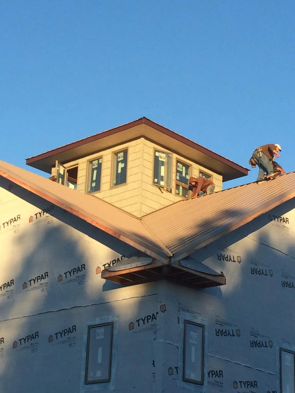 Roofers working around a rooftop cupola on a new metal roof at sunset — Roof Waterproofing in Cusseta by Roofing Brothers